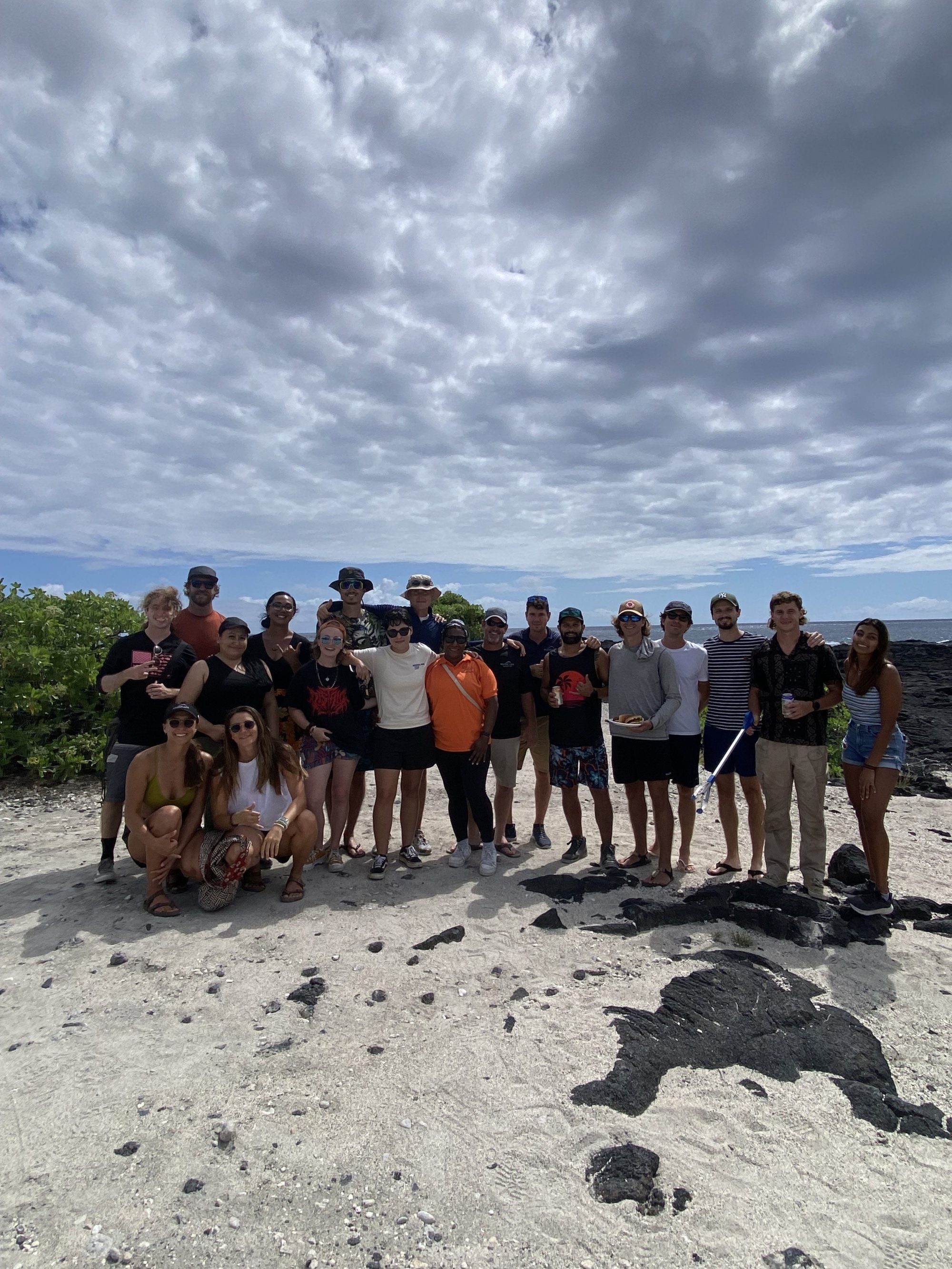 IMG_4605 a group of people standing on top of a sandy beach